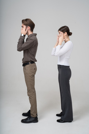 Side view of a  young couple in office clothing touching face