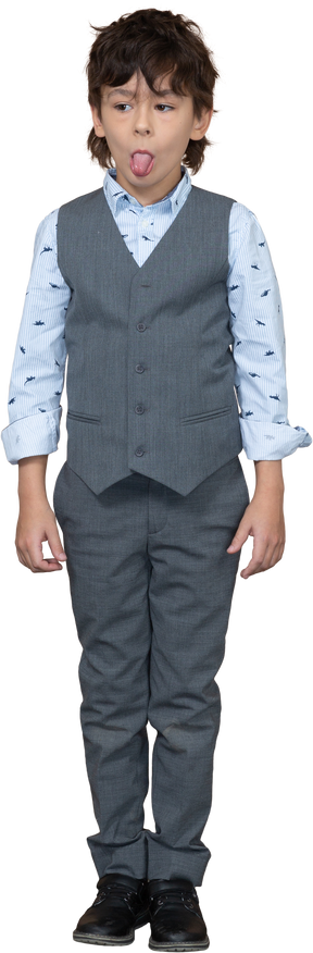 Vista frontale di un ragazzo carino in abito grigio che mostra la lingua e guarda da parte