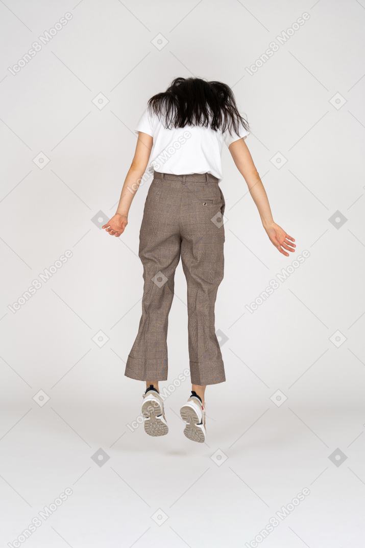 Back view of a jumping young lady in breeches and t-shirt looking down