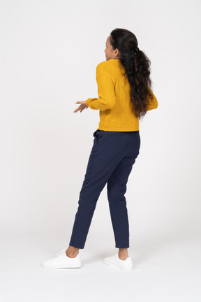 Back view of a girl in casual clothes standing with outstretched arms