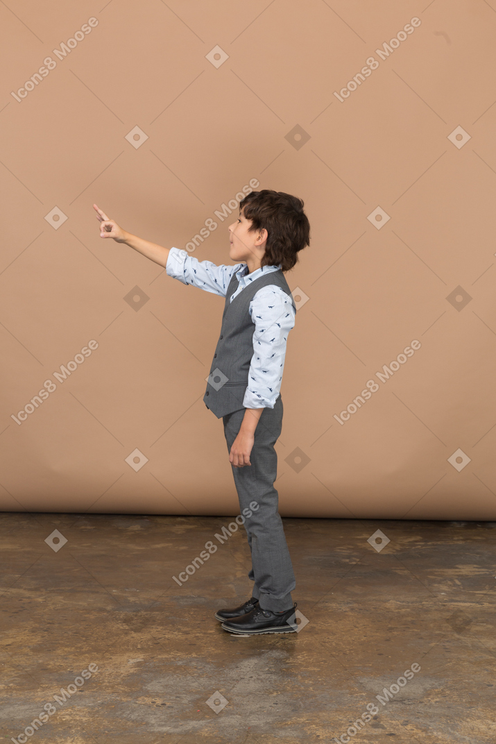 Side view of a boy in grey suit pointing
