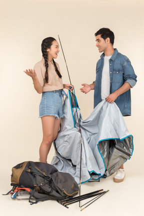 Rindo jovem casal interracial construindo uma tenda