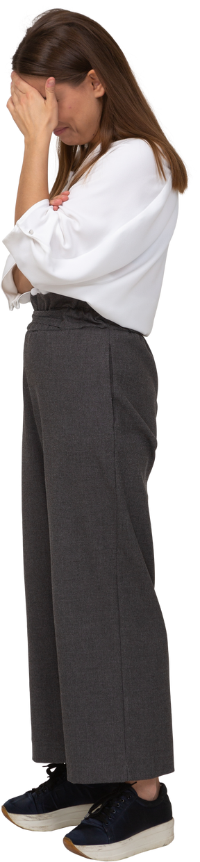 Side view of an upset young lady in office clothing hiding face