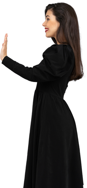 Seitenansicht einer lächelnden jungen grußdame in einem schwarzen kleid