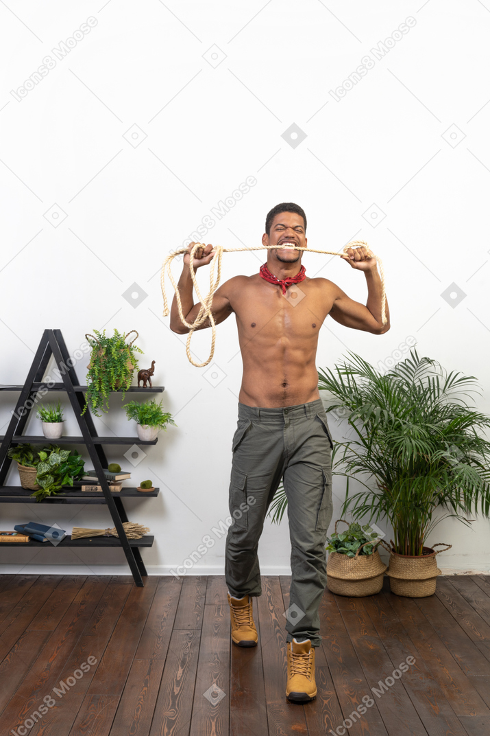 Front view of muscular man biting a rope