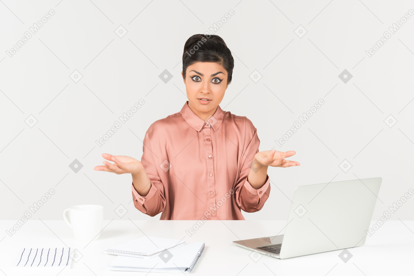 Surprised young indian office worker sitting at the desk