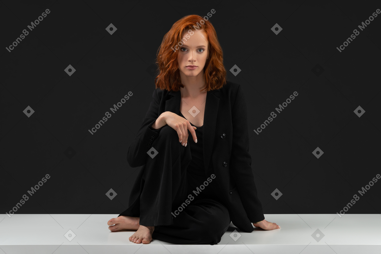 A frontal view of the young beautiful woman sitting on the table and looking to the camera