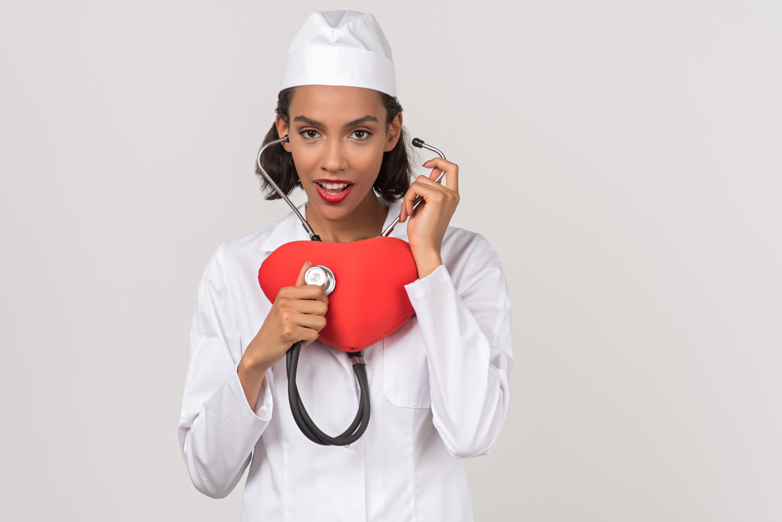 Attractive female doctor making auscultation of a toy heart