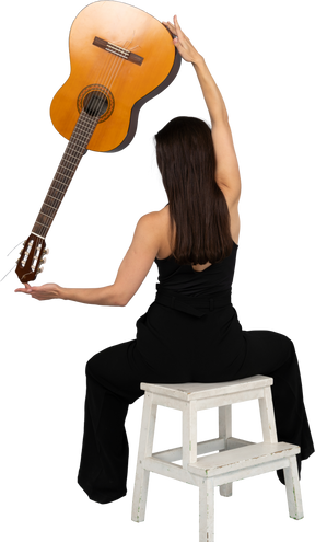 后面的观点的穿着黑色西装的年轻女士抱着吉他顶上，坐在凳子上