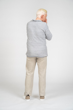 Back view of man covering his mouth with his hands