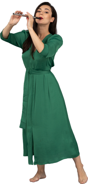 Vista di tre quarti di una giovane donna in abito verde che suona il flauto