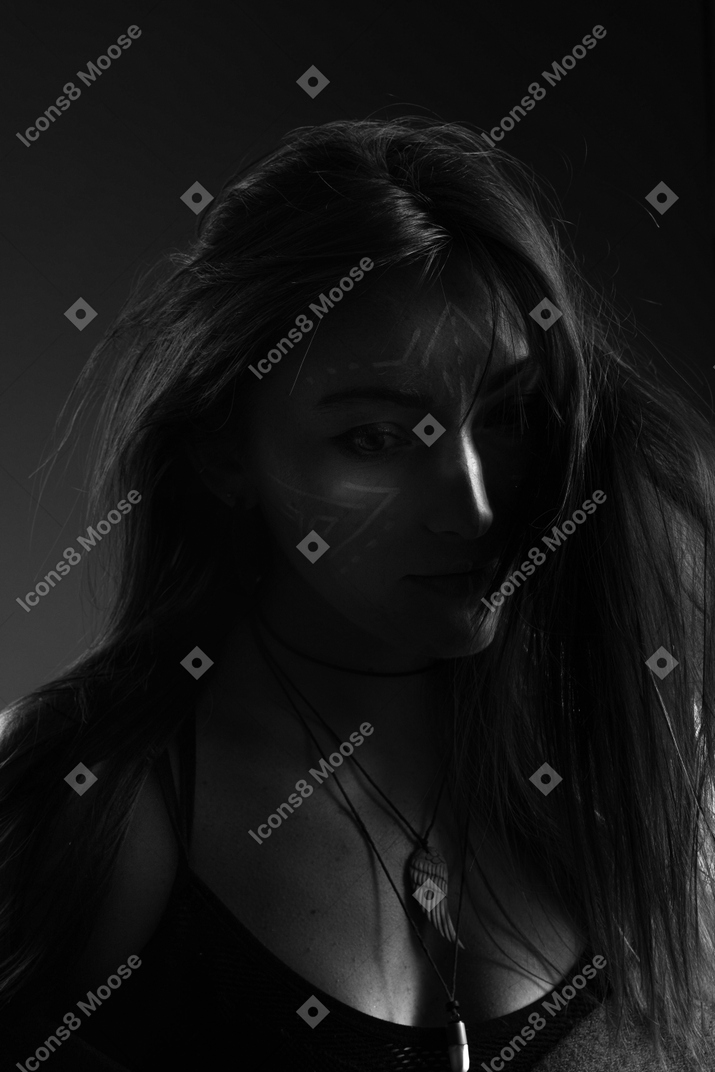 Dark silhouette of a young female with face art at lost