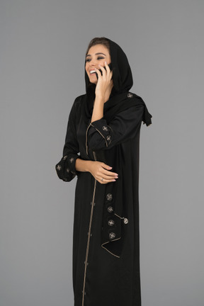 Donna musulmana sorridente che parla su un telefono