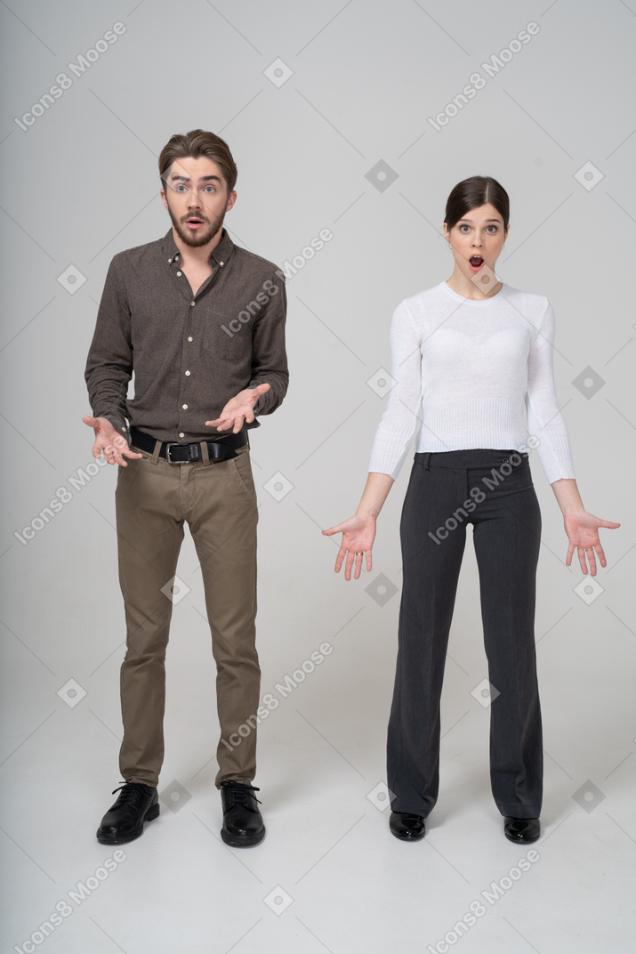 Vista frontal de um jovem casal surpreso com roupas de escritório