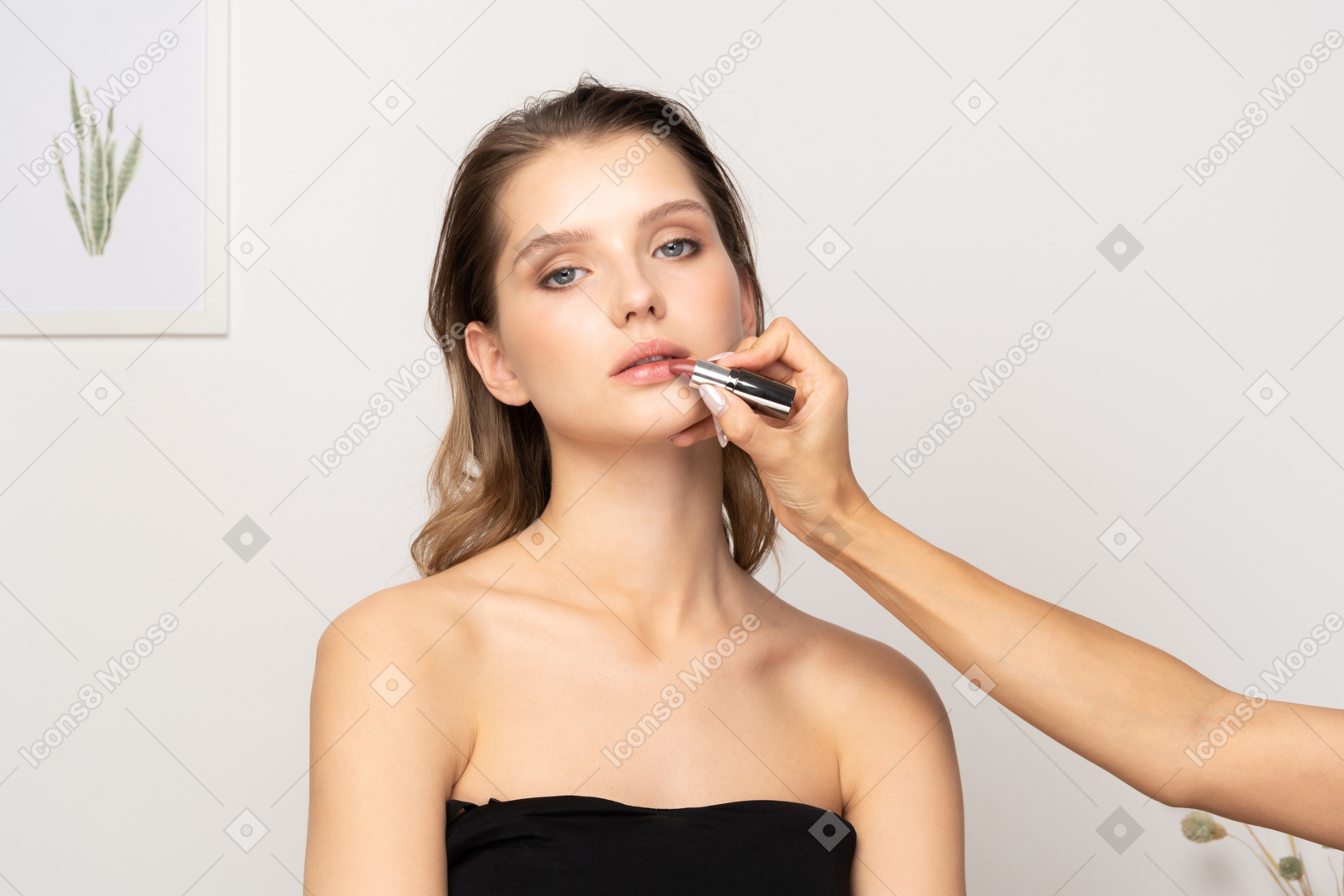 Front view of a make-up artist applying lipstick for a female model