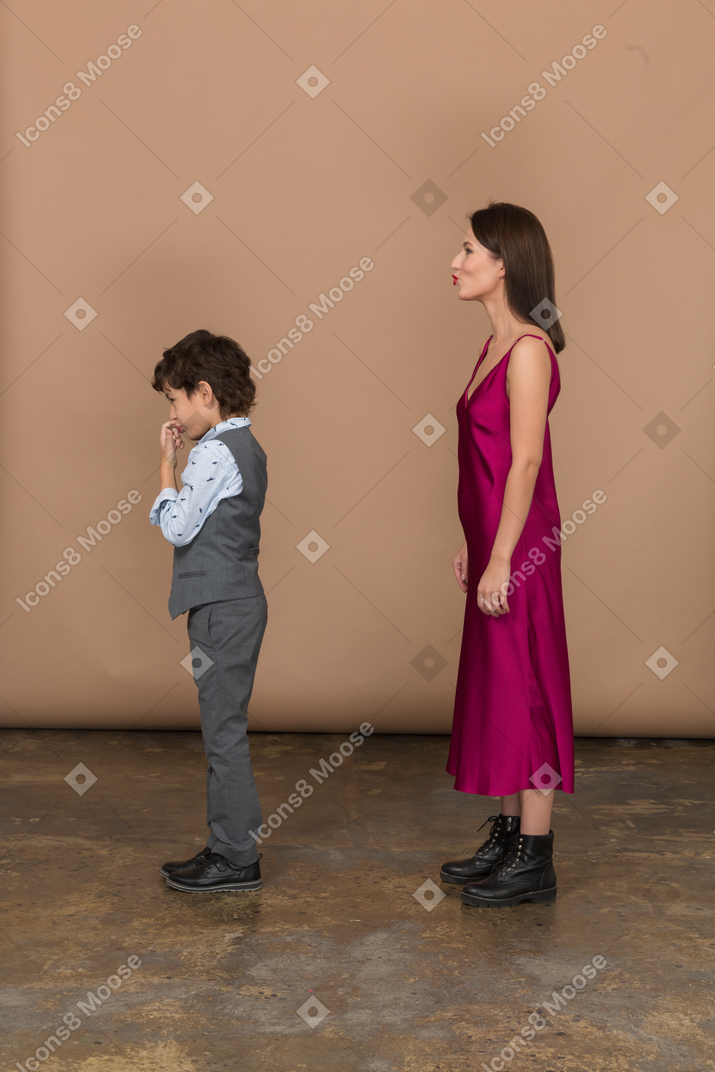 Woman in red dress and boy in grey suit vest in profile