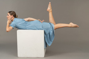 Vue latérale d'une jeune femme allongée sur un cube