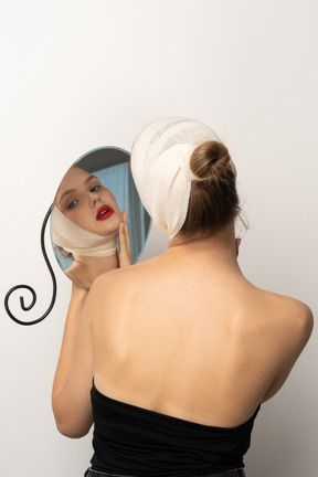 Young woman with head bandage holding a mirror