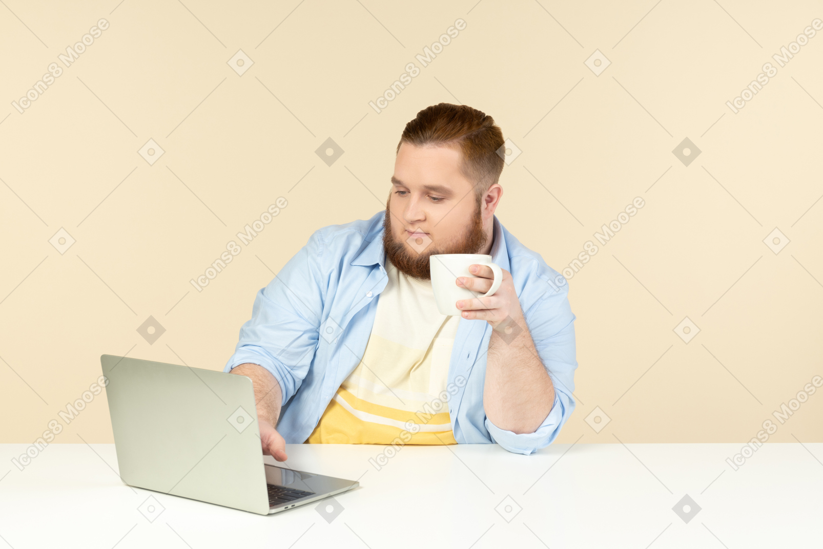 Young overweight man working on laptop and having tea