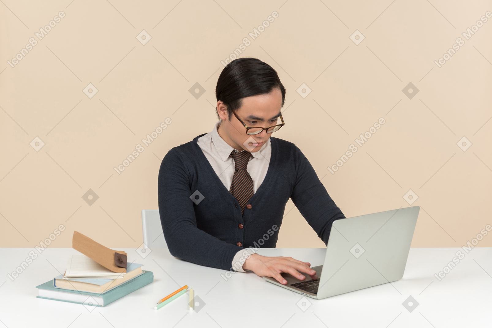 Young asian student in a sweater typing on a laptop