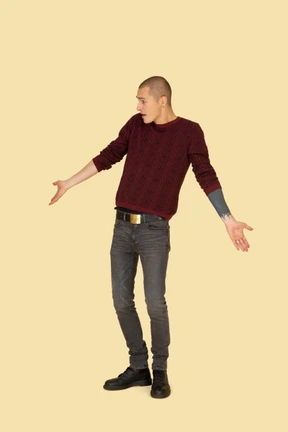 Front view of a young surprised man in red pullover outspreading his hands