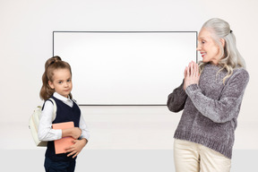 A woman standing next to a little girl in front of a white board