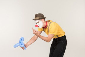 Male clown showing fuck to balloon figure he's holding