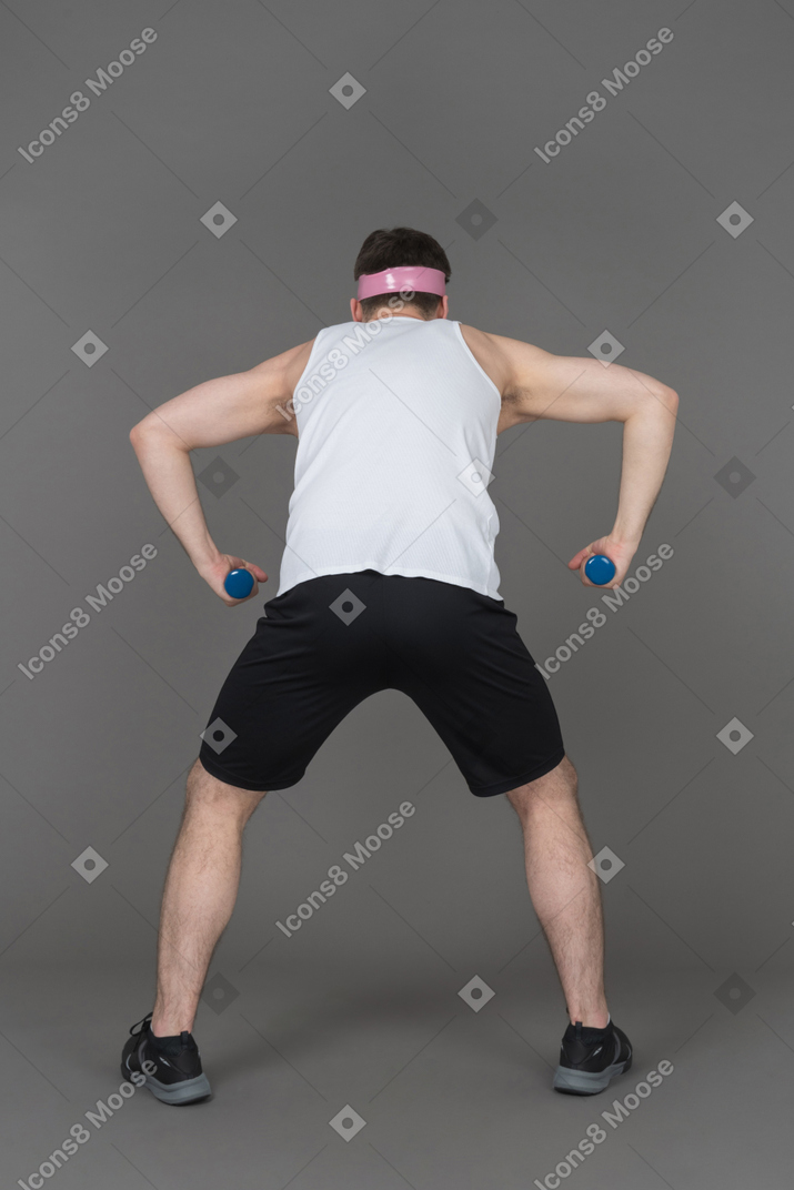 Man exercising with dumbbells back to camera