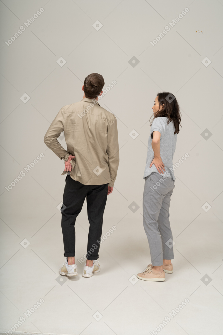 Young man and woman standing akimbo and looking away