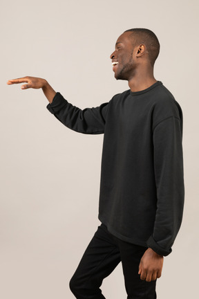 Side view of young man smiling and raising hand