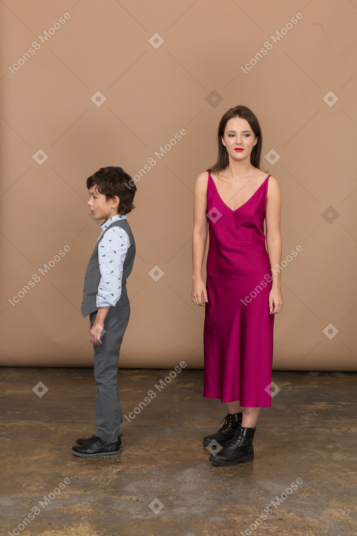 Молодая женщина смотрит в камеру, пока мальчик стоит рядом с ней