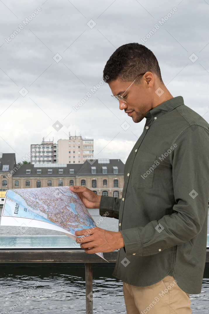 A man looking at a map in front of a body of water