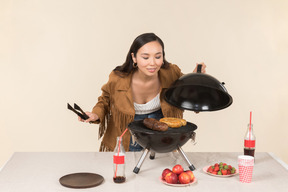 Joven asiática haciendo y oliendo barbacoa