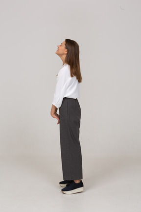 Side view of a smiling young lady in office clothing throwing head back