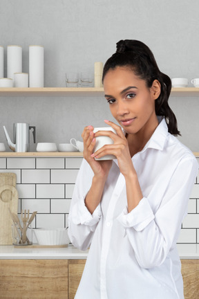 A woman in a white shirt is holding a cup