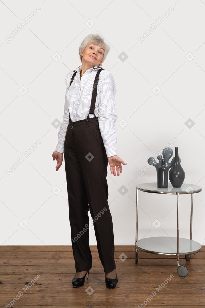 Three-quarter view of an old smiling lady in office clothing outspreading her hands