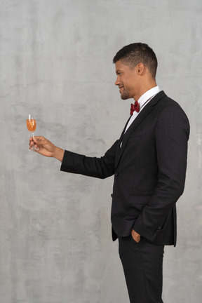 Vista lateral do homem com roupa formal, levantando um copo