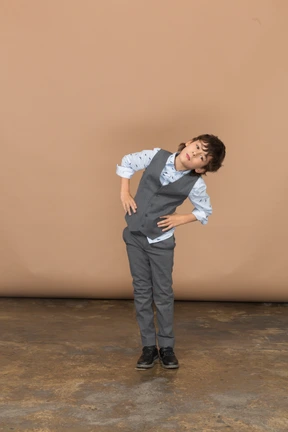 Front view of a boy in grey suit standing with hands on hips