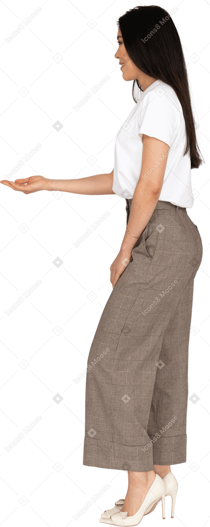 Seitenansicht einer jungen dame in reithose und t-shirt, die ihre hand ausstreckt