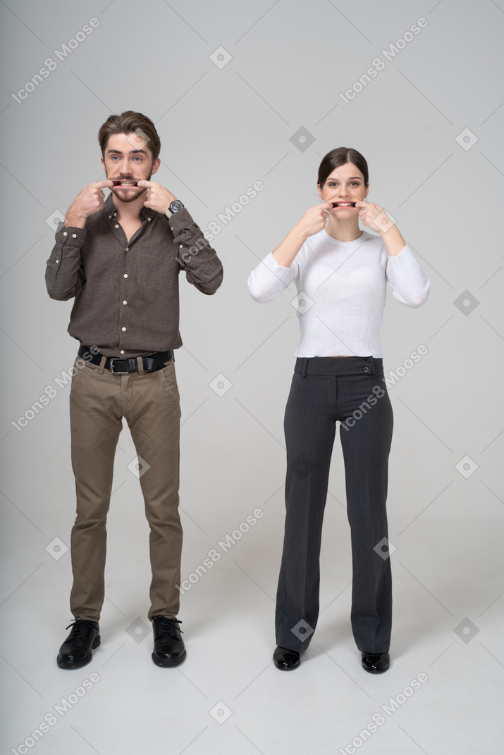 Front view of a young couple in office clothing stretching mouth