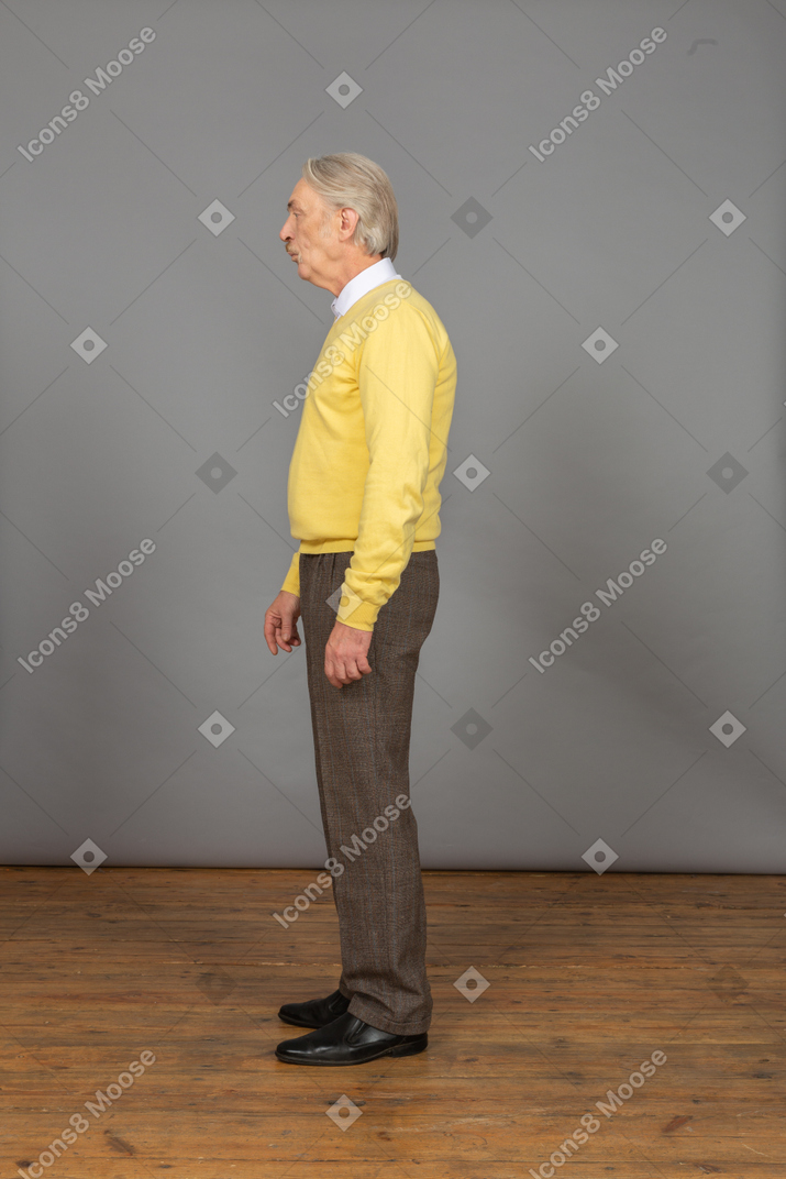 Side view of an old  pouting man in yellow pullover looking aside