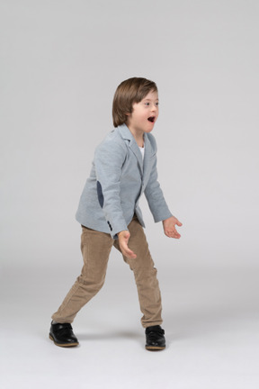 Young boy in blue jacket and brown pants screaming