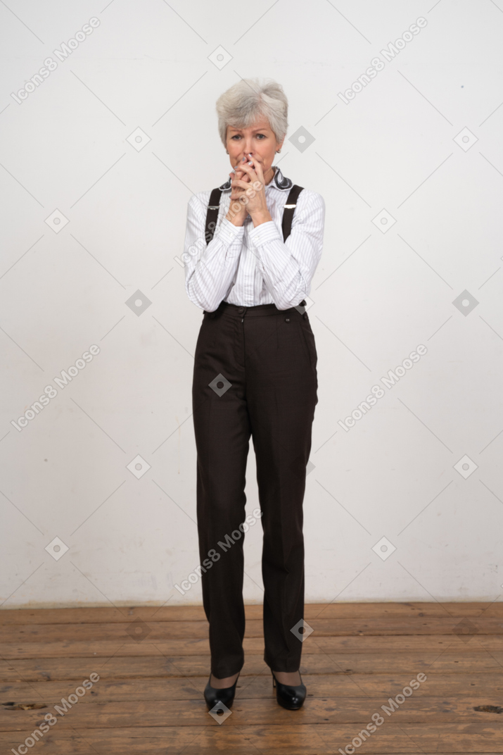 Vista frontal de uma senhora preocupada com roupa de escritório, de mãos dadas