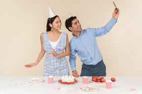 Молодая межрасовая пара делает селфи во время празднования дня рождения