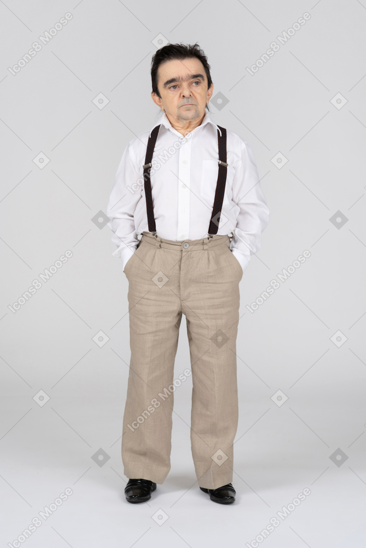 Mann mittleren alters mit händen in den taschen, die zur seite schauen