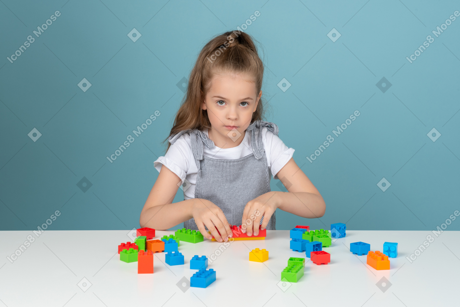 Little girl playing with building blocks and looking at camera