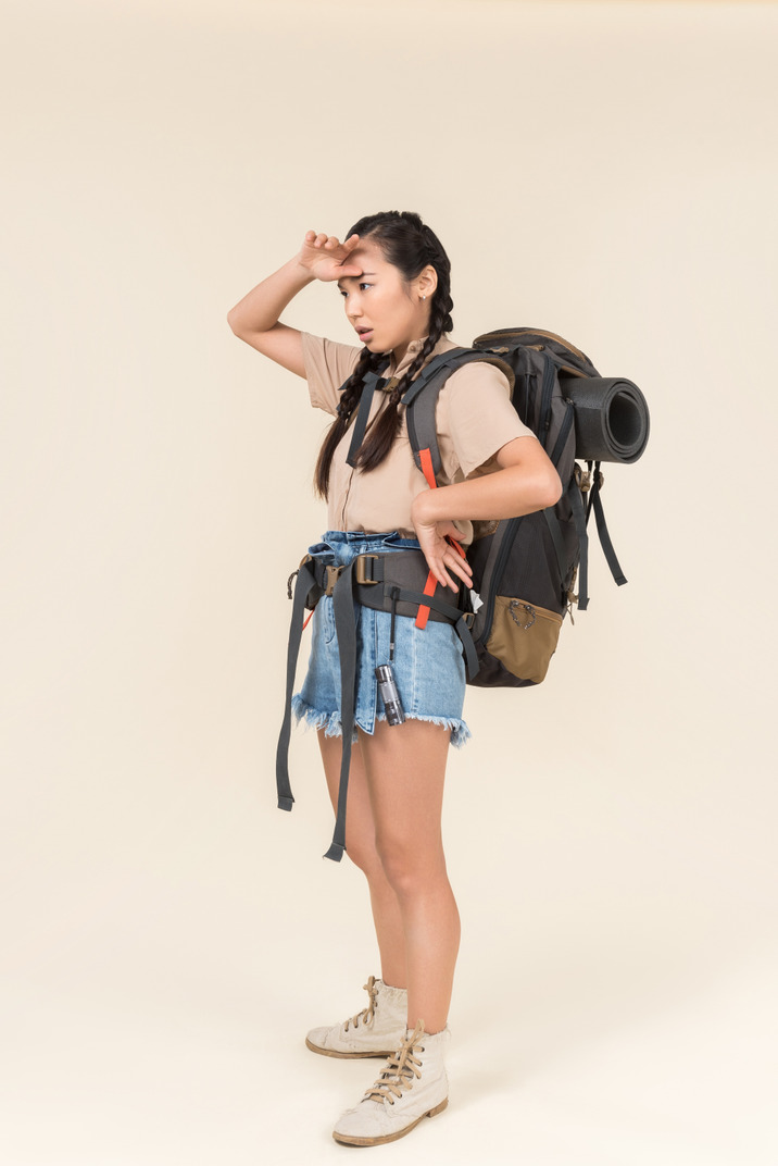 Tired looking young female asian hiker touching her forehead