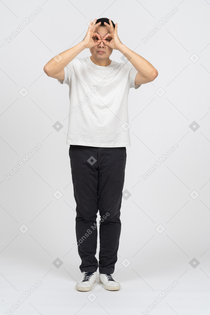 Vista frontal de um homem em roupas casuais, olhando para a câmera através de binóculos imaginários