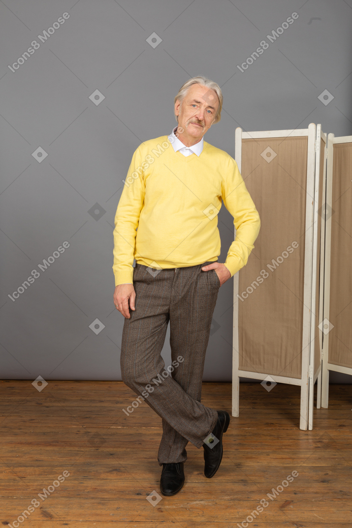 Vista frontal de un anciano poniendo la mano en el bolsillo mientras mira a la cámara