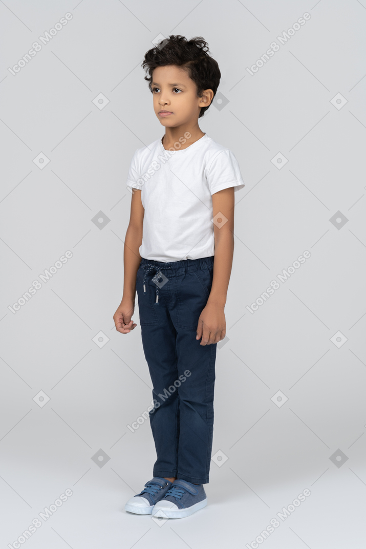 Un niño parado con las manos al lado del cuerpo